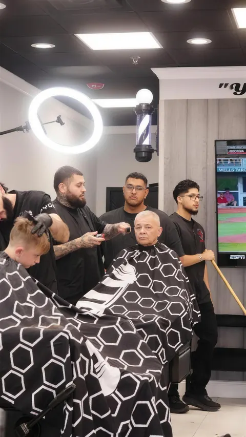 Three Top Style barbers working around one client in the chair