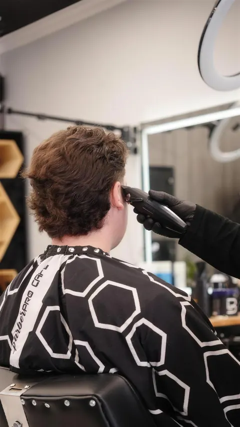 Barber tapering the sides of a client with full curls on top
