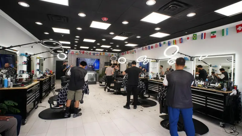 Wide view of the shop floor: black ceiling, flags, ring lights and barbers at every station