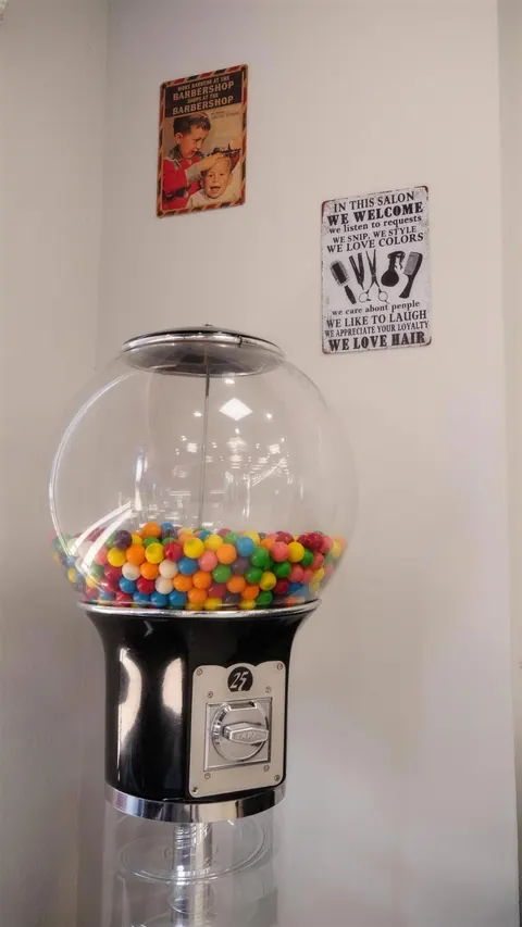 A gumball machine full of colored gum in the shop