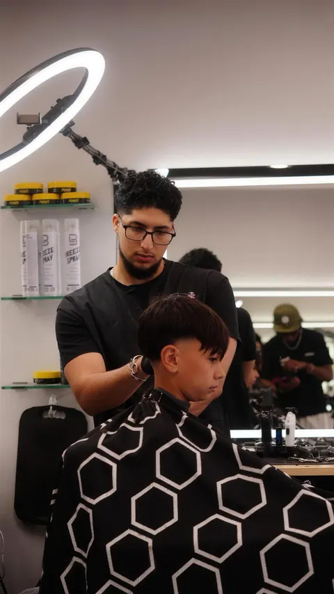 Barber shaping a boy’s fringe with a soft taper on the sides