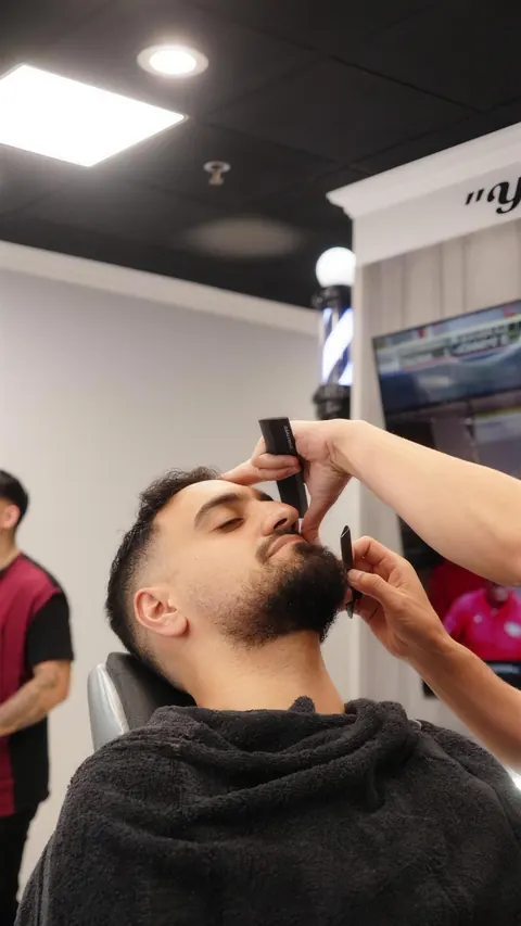 Barber lining up a client’s beard with a trimmer
