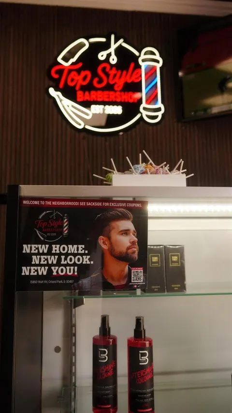 The neon sign above a glass shelf of products and the shop’s “New home. New look. New you!” poster