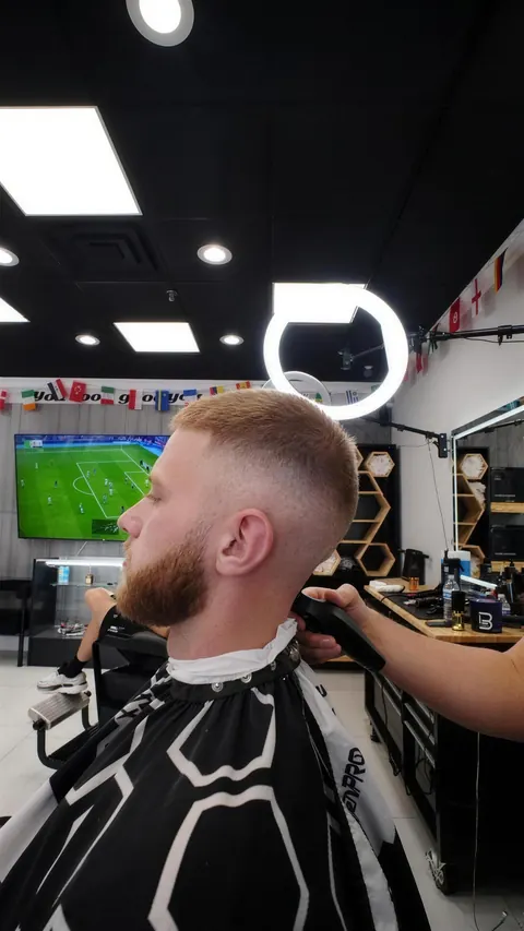 Back angle of a fade blending into a beard, the game on the TV