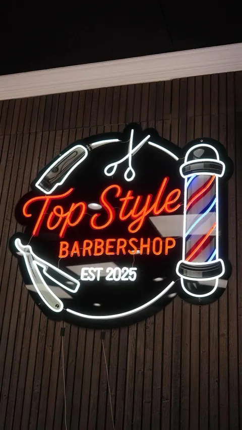 The Top Style Barbershop neon sign on dark wood slats, est. 2025