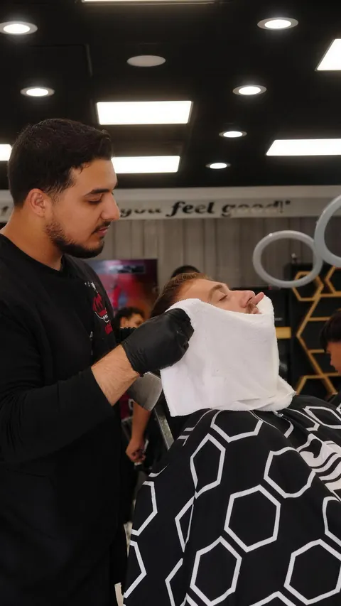 Barber laying a hot towel over a client’s face after a beard service