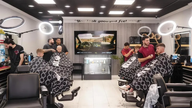 The back of the shop: the “You look good you feel good” sign, a barber pole, the TV and barbers at every chair